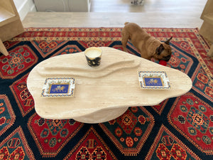 Top view of 3 layer natural light beige travertine wavy organic shape coffee table on red Patterned rug.