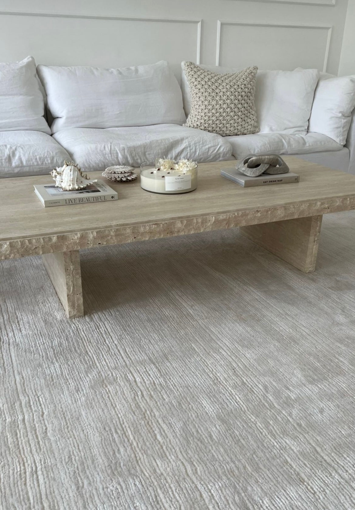 Raw edged light beige travertine coffee table in stylish living room.