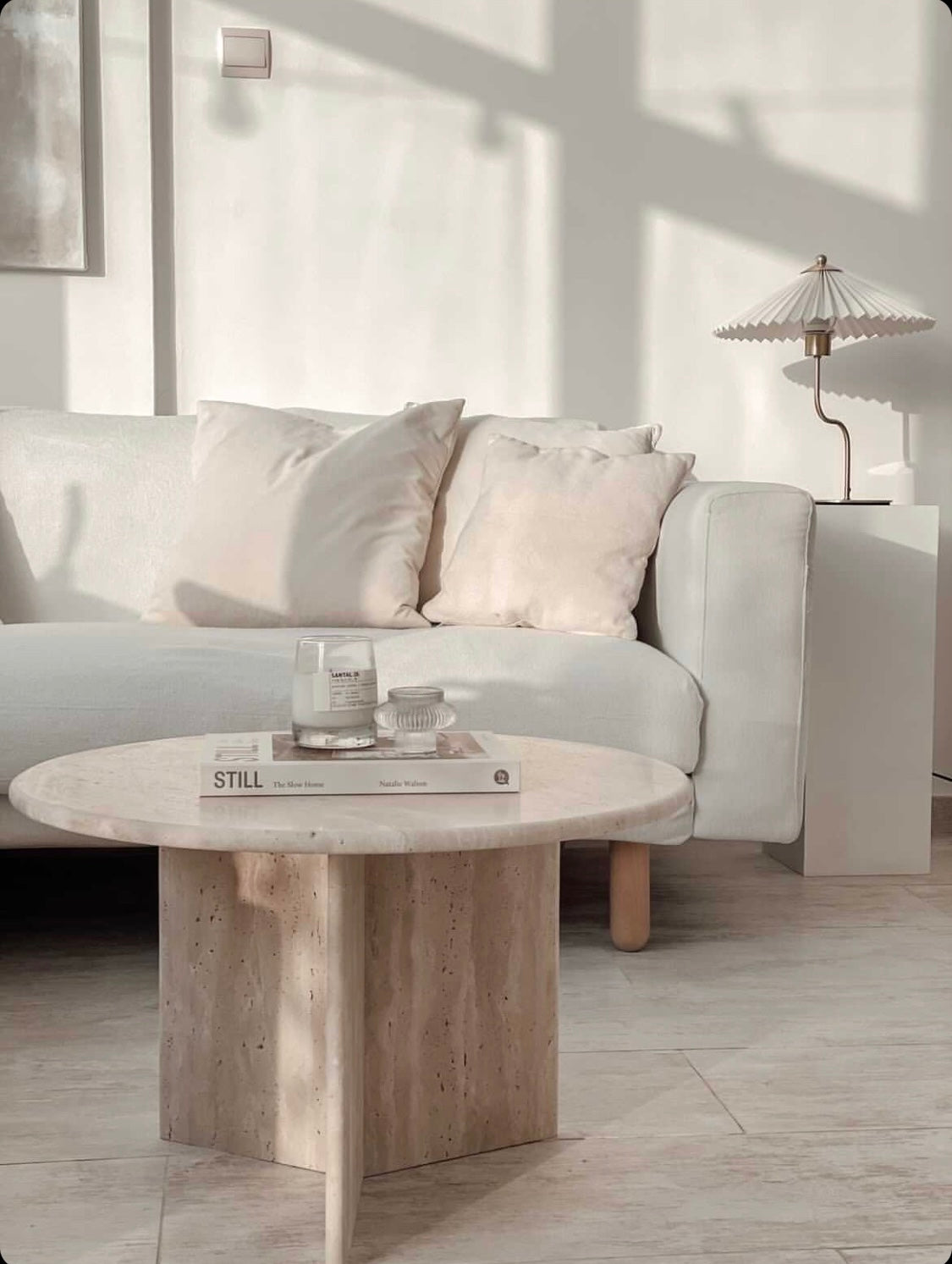 Round travertine coffee table with candle a book in living room