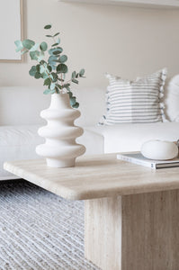 Light beige travertine coffee table with wavy vase and eucalyptus in comfy lounge