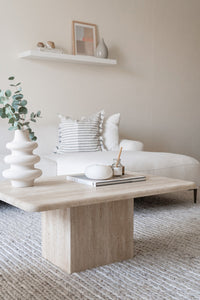 Rectangle travertine coffee table with cube base in stylish room.