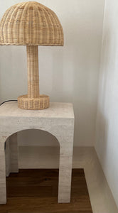 Close up travertine table with arched base and wicker lamp,