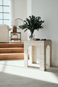 Light beige travertine side table with arched base.