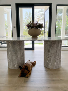 2 cylinder fluted fior marble table bases with french bulldog lying down in front.