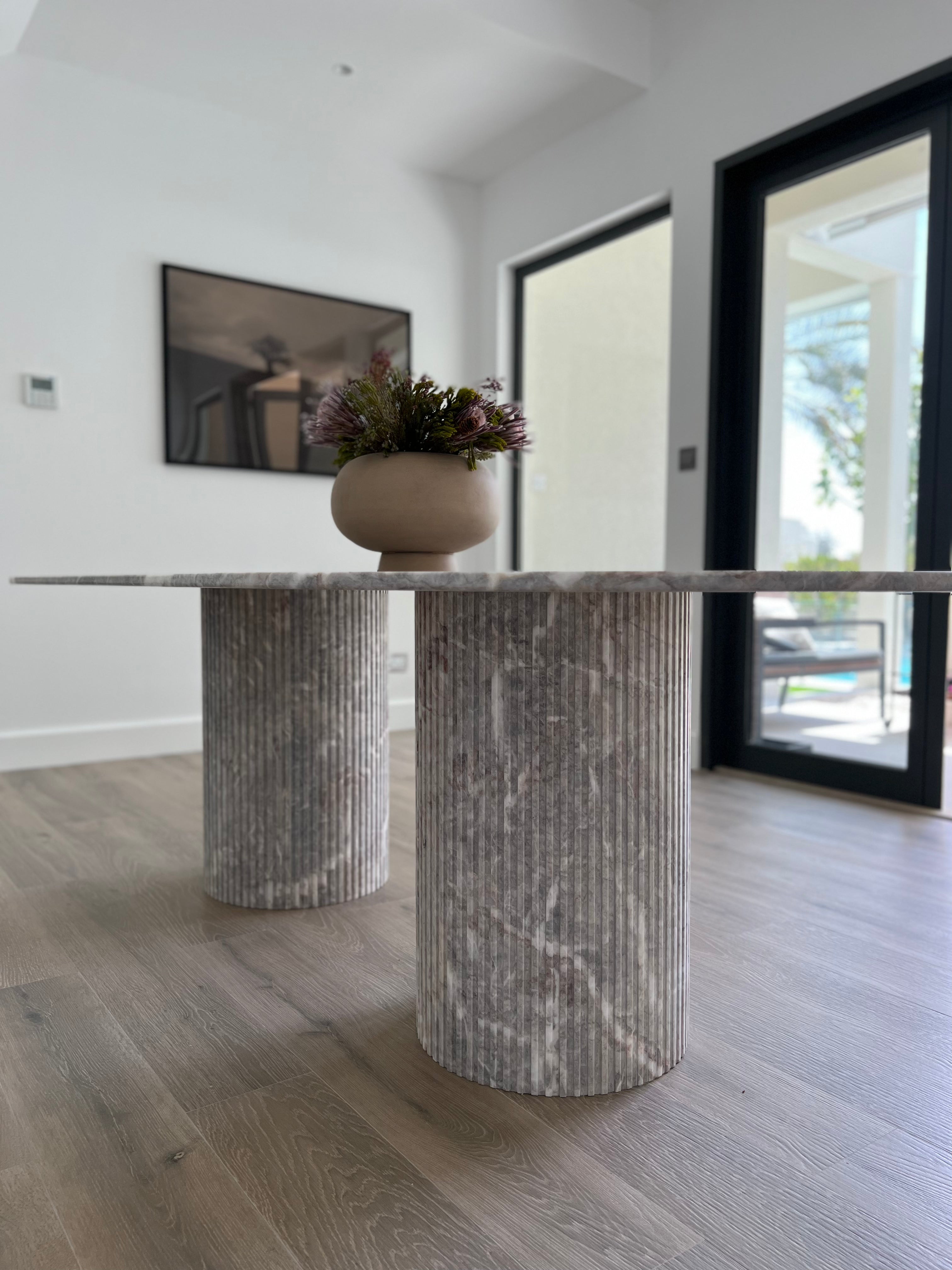 Side angle of fluted marble based dining table in grey and white stone.