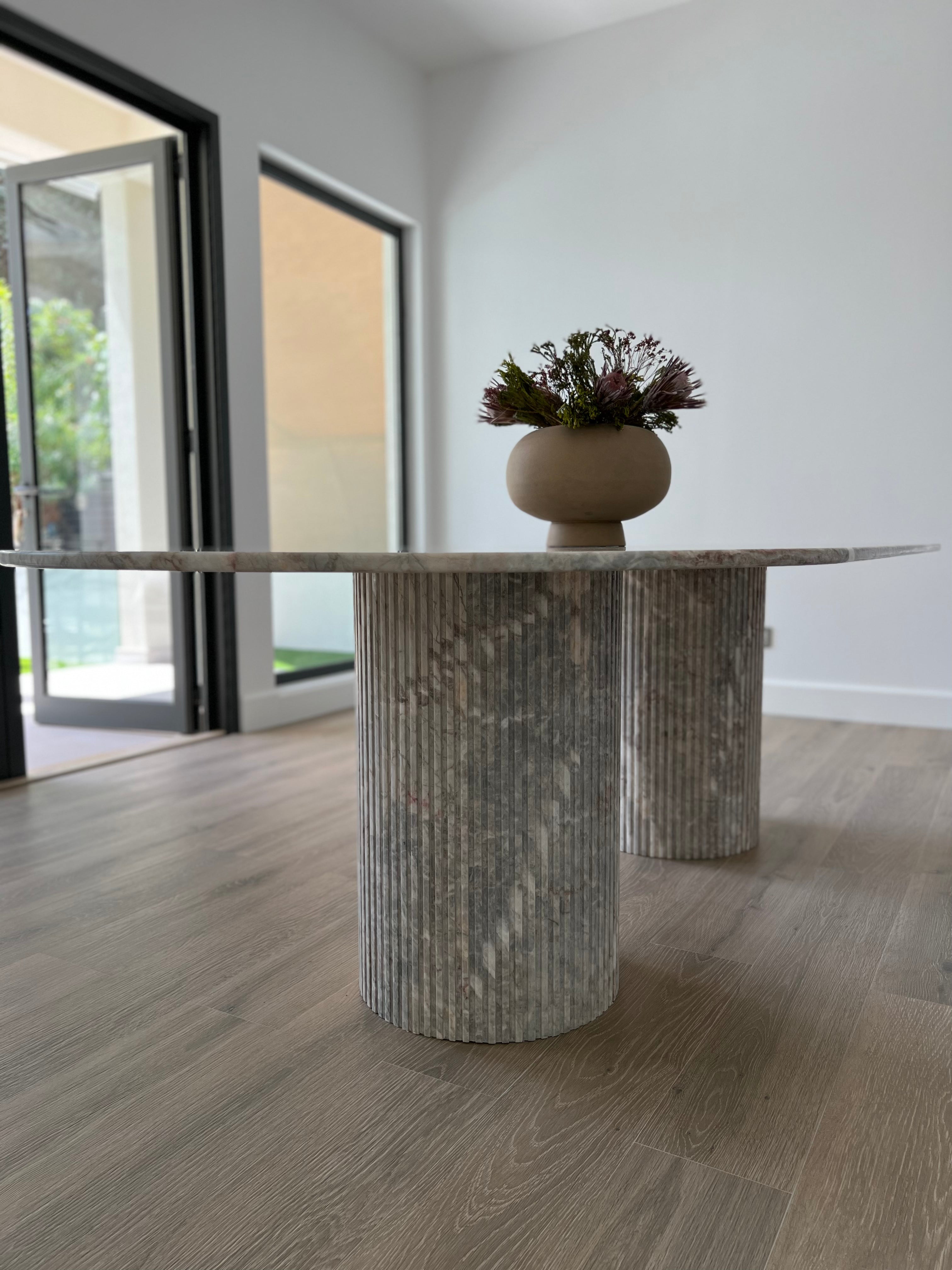 Fluted cylinder greek marble bases on oval dining table.