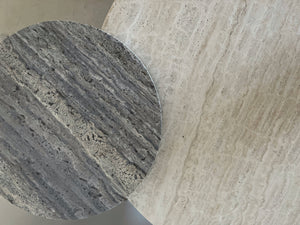 Round light beige and smaller round silver travertine table tops overlapping. 