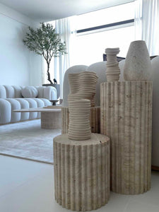 3 varying height travertine fluted pedestals, in stylish room 