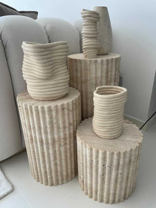 3 varying height fluted travertine plinths with ribbed clay pots