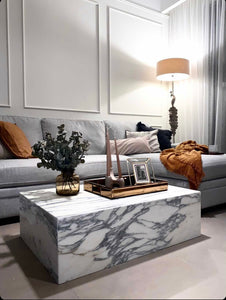 Grey and white arabascato marble cube coffee table in chic panelled living room in evening.