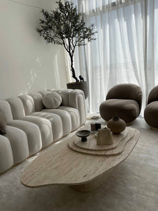 Unique organic shaped natural travertine coffee table with 3 levels and oval base, in designer living room.