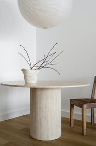 Light beige travertine 4 seater round dining table with cylinder base, with wooden dining chair.